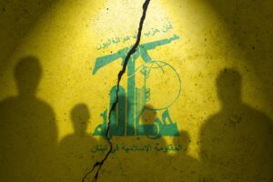 Flag of terrorist organization Hezbollah painted on the concrete wall with humans shadows. Terrorist organization Hezbollah.